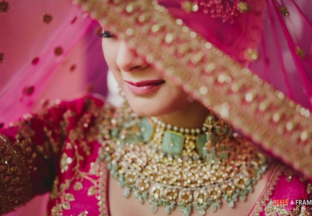 Photo of Bride posing in light pink lehenga and contrasting green jewellery